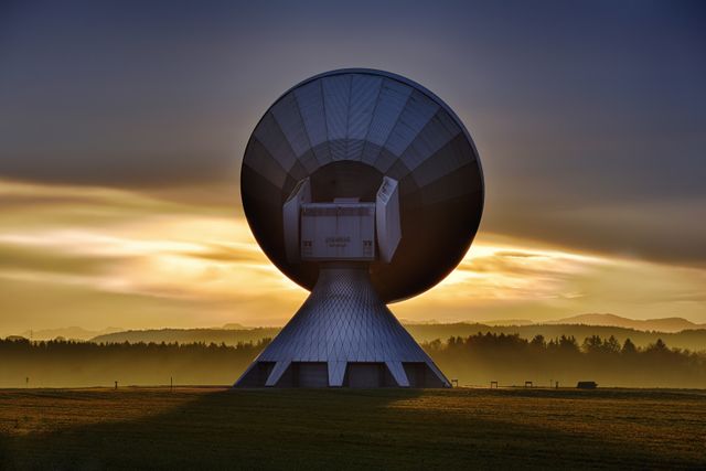 Large satellite dish against landscape at sunrise
